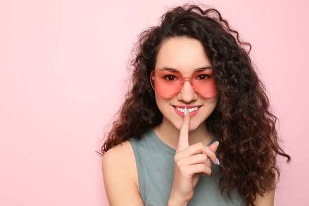 Portrait of beautiful young woman wearing sunglasses on pink