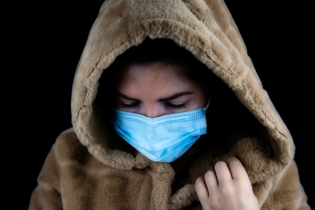 Portrait of a beautiful young woman wearing a winter jacket with medical mask