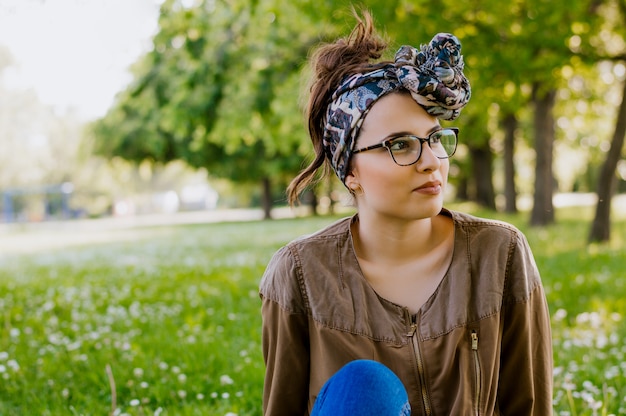 Портрет красивой молодой женщины, которая сидит на зеленой траве