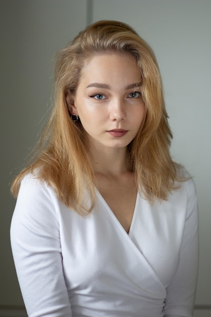 Portrait of the beautiful young woman in white dress looking at camera,