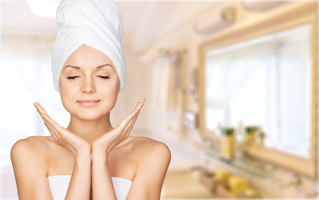 Portrait of beautiful young woman  in white towel on head on  background