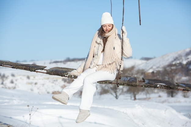 Portrait of a beautiful young woman in white winter clothes on nature