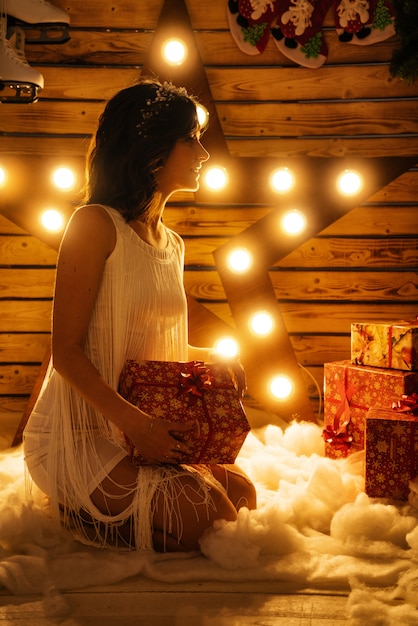 Portrait of a beautiful young woman who holds a gift for new year and Christmas.