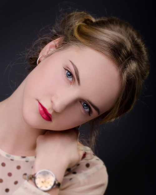 暗い背景に青い目とブロンドの髪を持つ美しい若い女性の肖像画