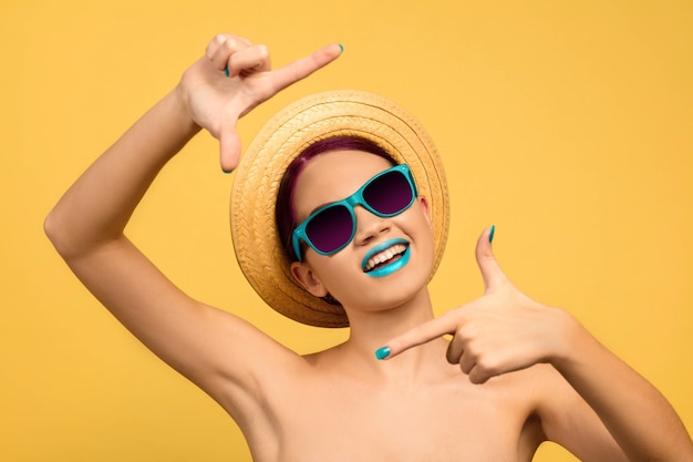 Portrait of beautiful young woman with bright make-up isolated on yellow studio background