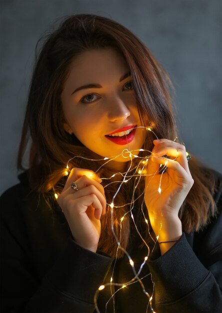 Portrait of a beautiful young woman with Christmas lights