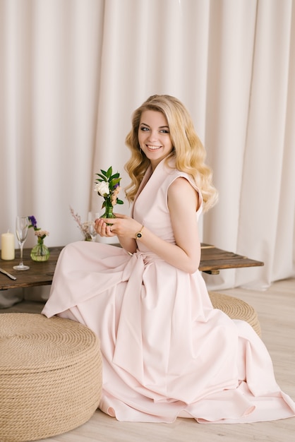 Portrait of a beautiful young woman with curly blonde hair in a delicate dress