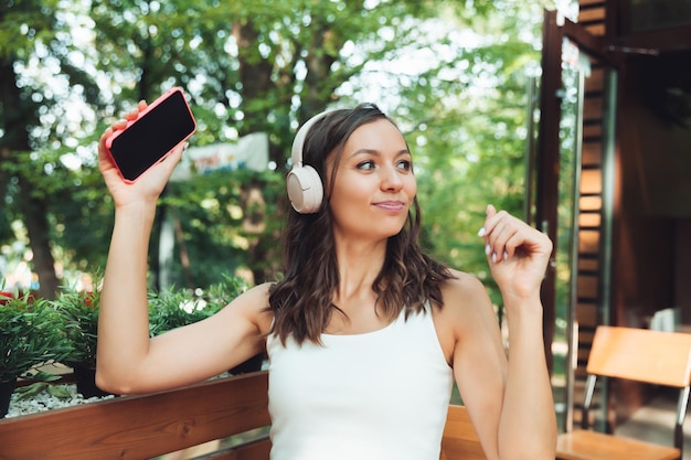 Portrait of a beautiful young woman with headphones who listens\
to music while sitting in a street cafeenjoy the music generation\
z