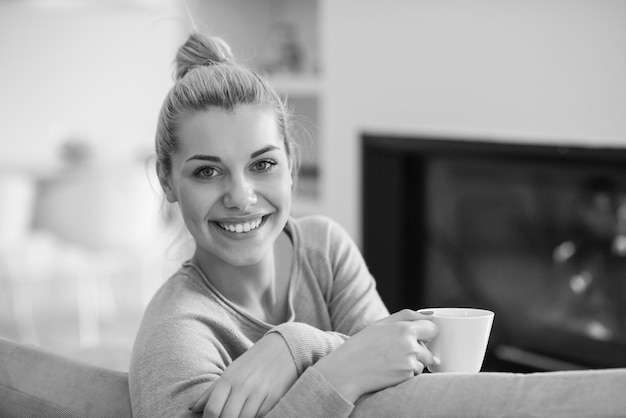 Portrait of beautiful young woman with a mug near a fireplace