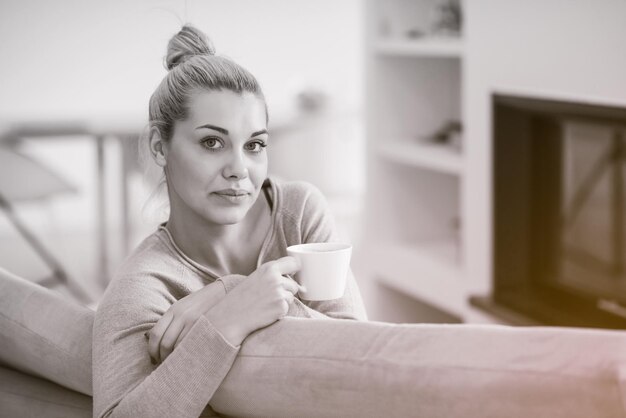 Portrait of beautiful young woman with a mug near a fireplace