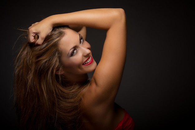 Portrait of a beautiful young woman with nice make up posing in a studio on dark background.