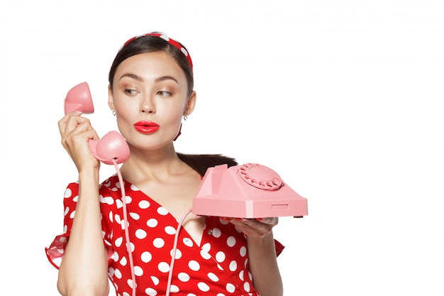 Portrait of beautiful young woman with phone, dressed in pin-up style.