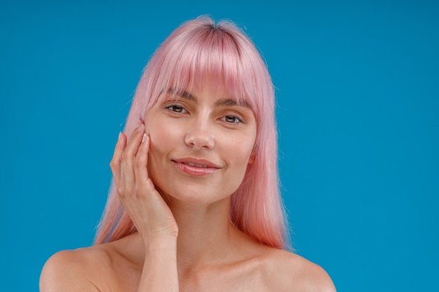 Portrait of beautiful young woman with pink hair and perfect skin looking at camera posing isolated