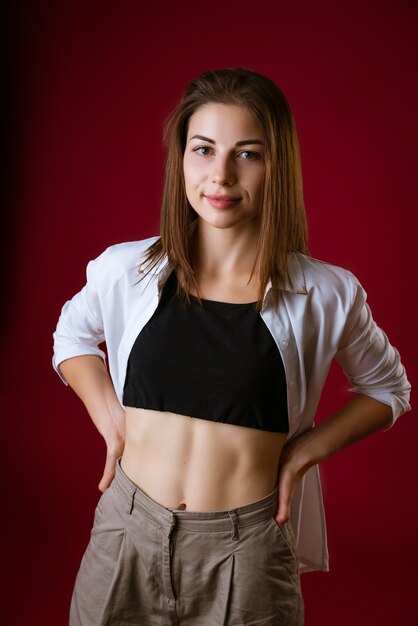 Portrait of a beautiful young woman with a press on the abdomen posing on a red space