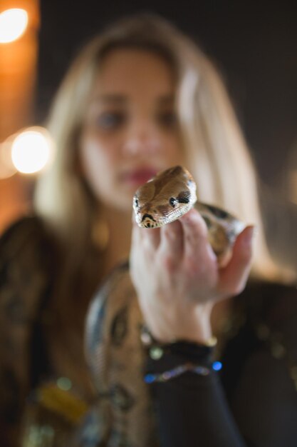 Portrait of beautiful young woman with a python on face close up