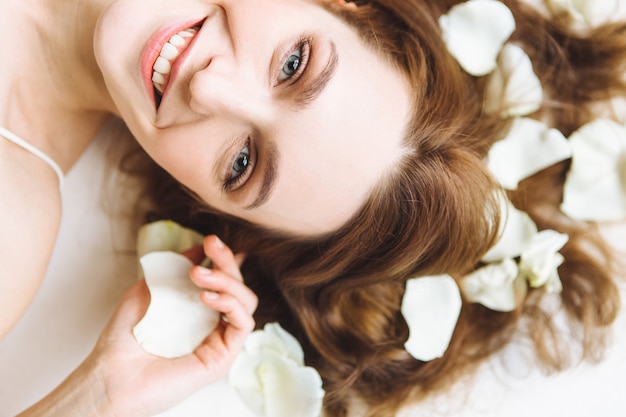 Portrait of beautiful young woman with white rose petal on white background. Relax and spa