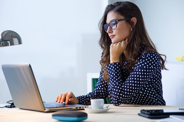 Portrait of beautiful young woman working with laptop in her office.