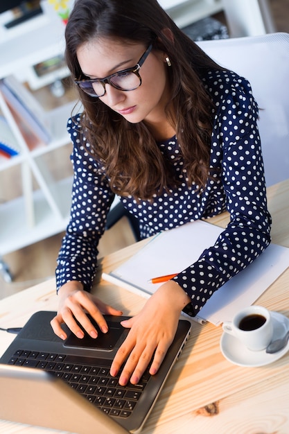 Portrait of beautiful young woman working with laptop in her office.