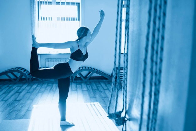 Portrait of a beautiful young woman in yoga pose holding her leg