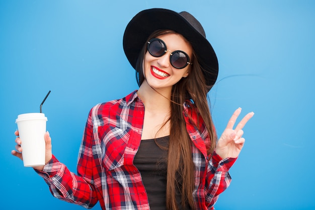 Photo portrait of beauty fashion smiling woman with coffee, making peace by fingers in sunglasses  . outdoor