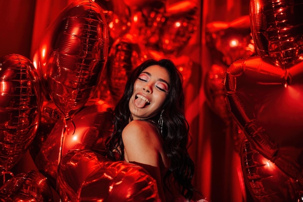 Портрет красивой гламурной азиатской сексуальной улыбки девушки в нижнем белье на фоне блестящих красных надувных шаров