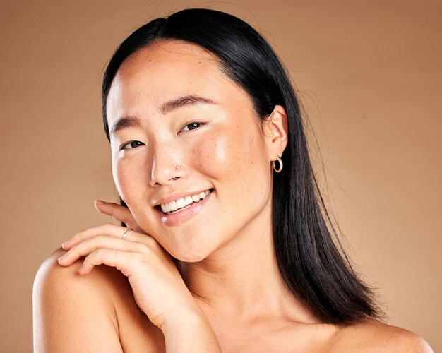 Portrait beauty and treatment with a model asian woman in studio on a beige background for natural skincare Wellness aesthetic or facial with an attractive young female posing to promote antiaging