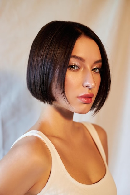 肖像画の美しさの女性の短い髪のファッションの着色。ダークヘアカラー、ショートヘアカットチョコレートカラー。美しいきれいな顔の肌、自然なメイク、強い髪