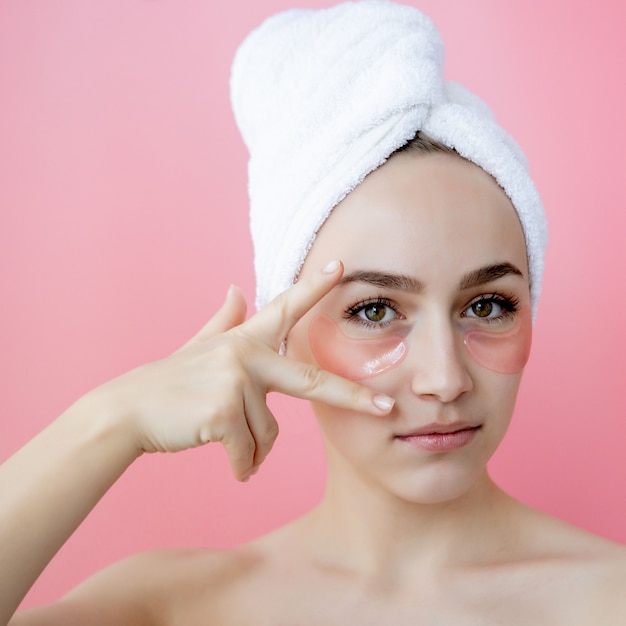 Foto ritratto della donna di bellezza con le toppe dell'occhio su fondo rosa. fronte di bellezza della donna con la maschera sotto gli occhi. cura della pelle, concetto di prodotto cosmetico