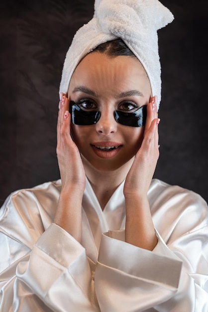 Portrait of beauty young woman doing anti aging procedures with eye patches for perfect skin isolated on dark Skin care concept