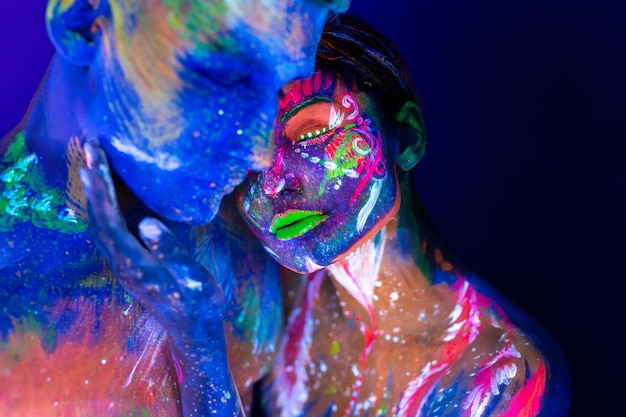 Portrait of a beefy man and woman painted in ultraviolet powder. Body art glowing in ultraviolet light