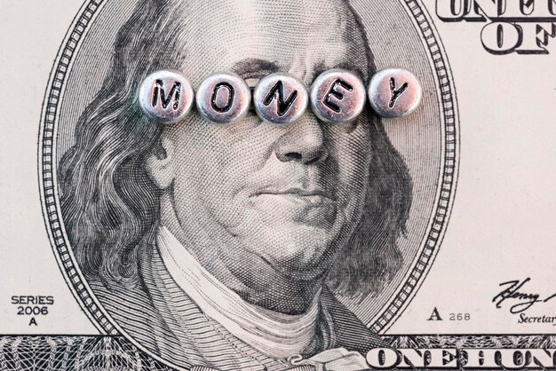 銀のビーズで作られた「お金」と刻まれた100ドル紙幣のベンジャミン・フランクリンの肖像画