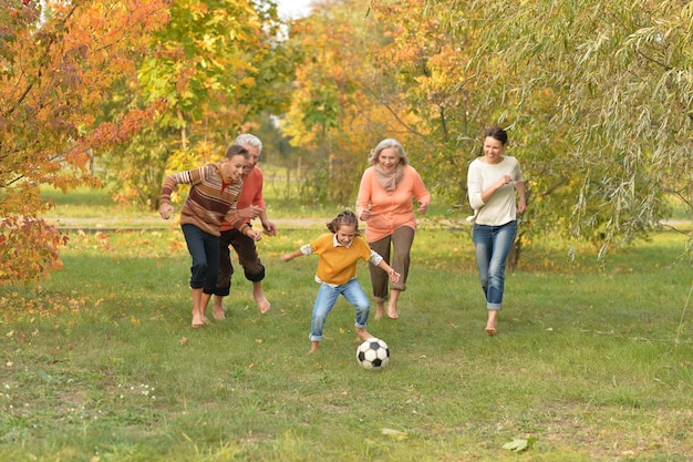 Портрет большой счастливой семьи, играющей в футбол в парке