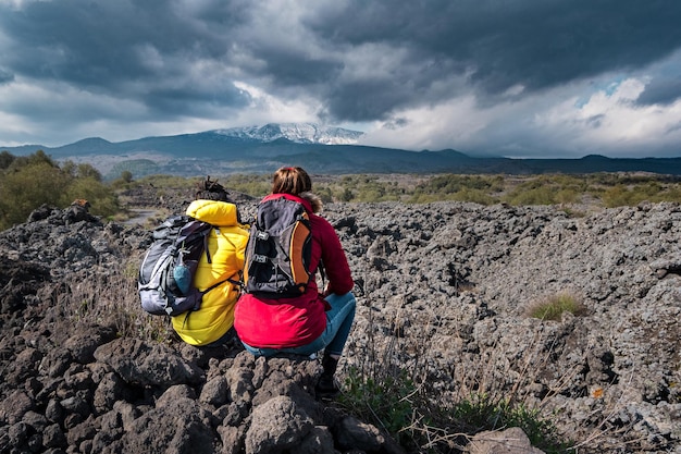 Portrait of biracial couple of young people hiking in Sicily Italy walking on the lava stone of the Volcano Etna wanderlust travel and lifestyle concept