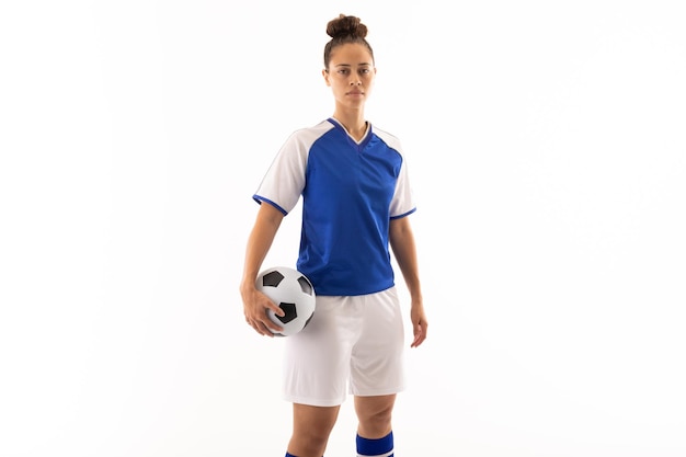 portrait of biracial young female soccer player with soccer ball standing against white background