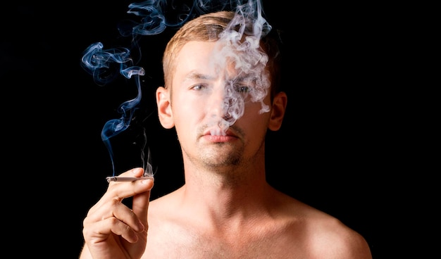 Foto ritratto su sfondo nero il ragazzo con una sigaretta in mano fuma