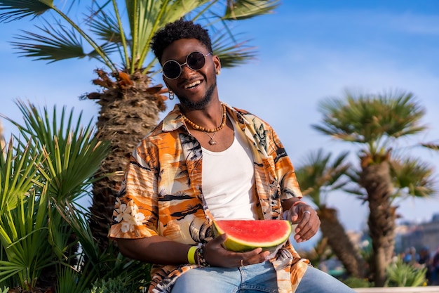 Portrait of a black ethnic man enjoy summer vacation on the beach with a watermelon having fun