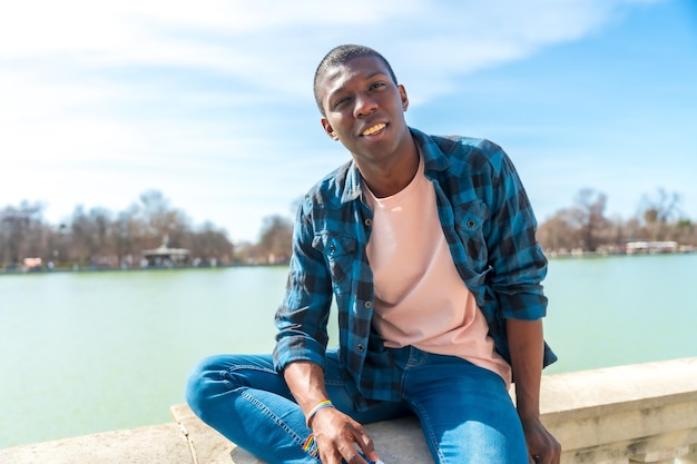 Portrait of a black ethnic man in summer by a city lake enjoying vacation