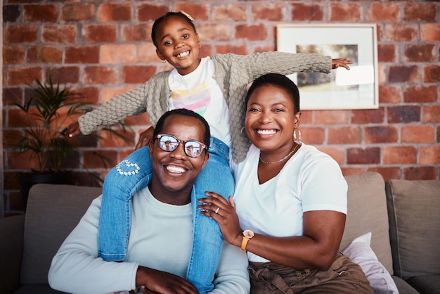 Photo portrait of black family in home parents and kid on sofa with piggy back bonding and relax in lounge mom dad and girl child on couch in apartment with playful man woman and daughter together