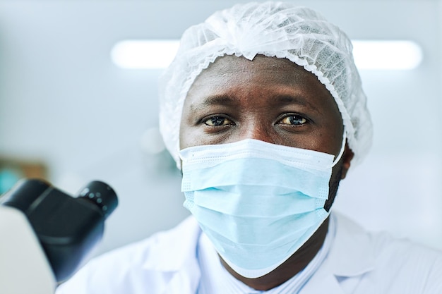 Portrait of black man wearing face mask and looking at camera while working in medical laboratory