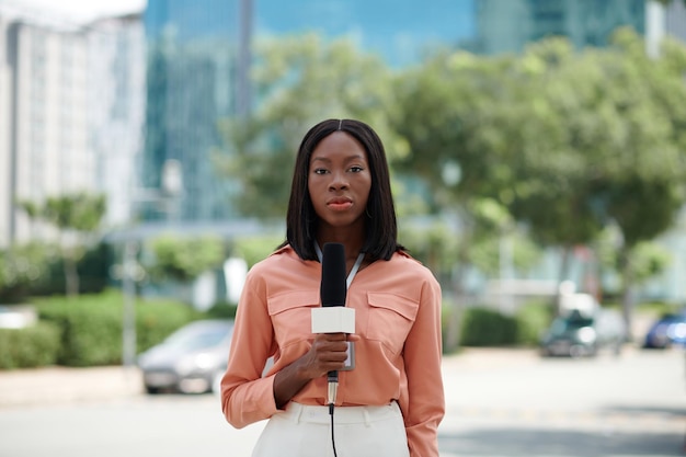 Portrait of Black serious journalist speaking in microphone