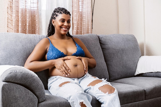 Portrait of black woman with braids holding with hands her pregnant belly