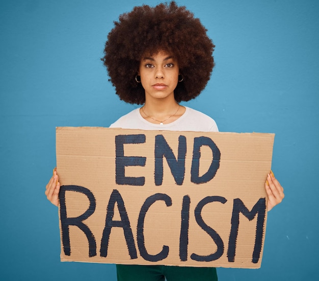 Photo portrait of a black woman with a stop racism banner and peacefully protesting for human rights in studio young afro girl with a cardboard poster fighting for race social justice or racial equality