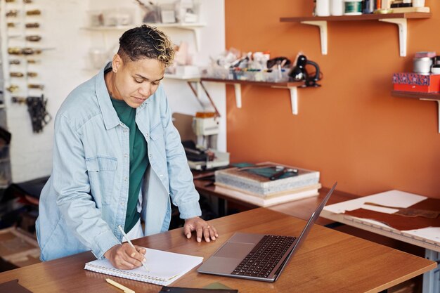 Portrait of black woman writing in planner while managing small business manufactory copy space