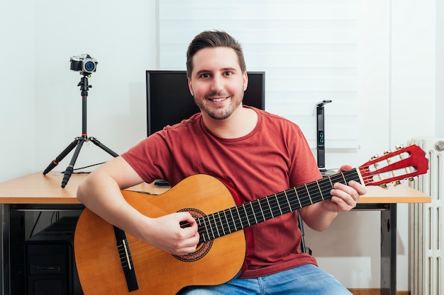 Portrait of a blogger playing guitar from his home recording studio.