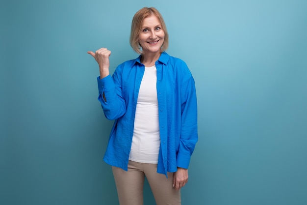 Портрет блондинки привлекательной женщины средних лет в повседневной стильной рубашке на синем фоне с