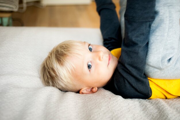 Portrait of a blond boy of five years lying in bed close-up