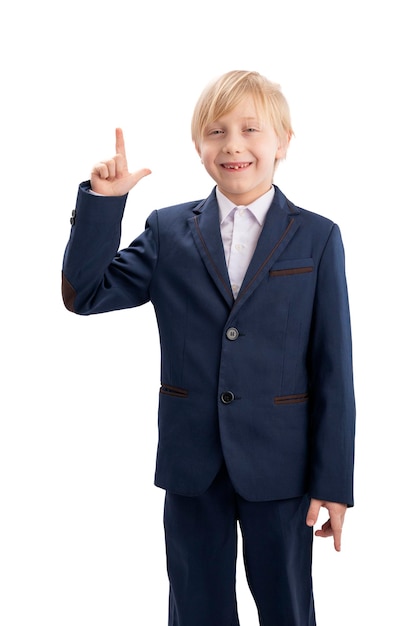 Portrait of blond boy in school uniform with hand raised up isolated on white background Vertical frame Bright student