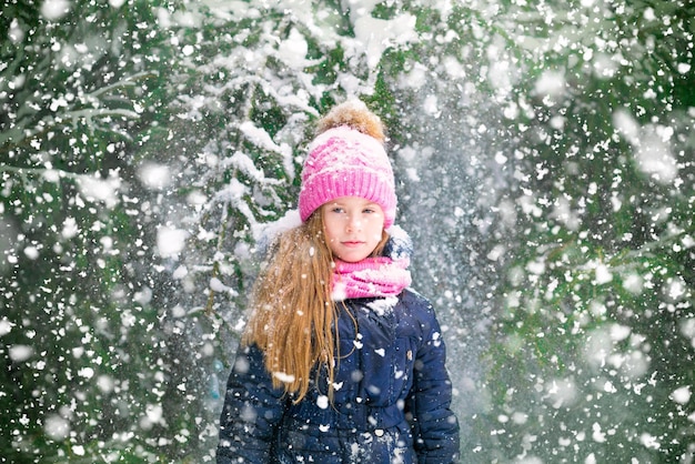 A portrait of blond girl kid over firtrees background