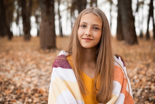 Portrait of a blond girl in warm plaid in the park