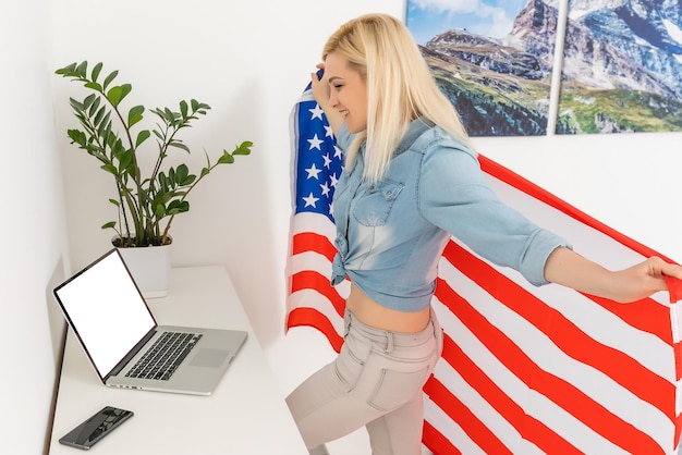 Portrait of a blond girl with USA flag with laptop.